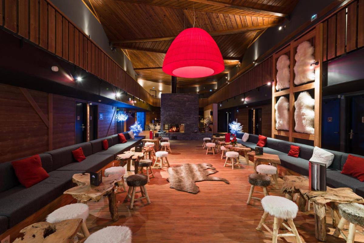 un restaurant avec des tables et des chaises et une lumière rouge dans l'établissement Marmotel & Spa, à Pra-Loup