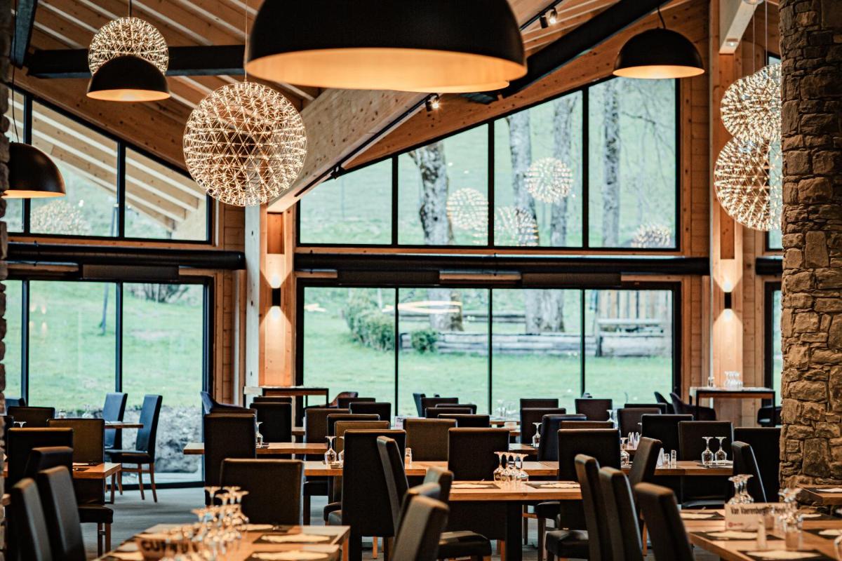 un restaurant avec des tables et des chaises et de grandes fenêtres dans l'établissement Hotel Club Le Crêt, à Morzine