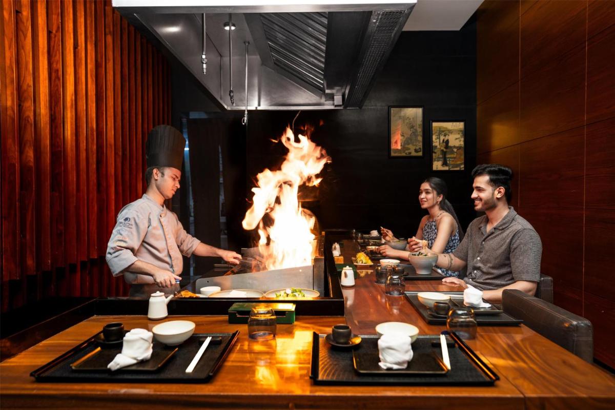 a group of people sitting around a table with a fire at DoubleTree by Hilton-Pune Chinchwad in Pune