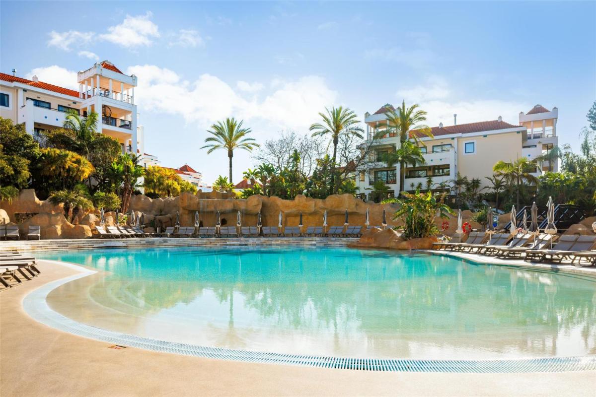 uma piscina num resort com cadeiras e palmeiras em Hilton Vilamoura em Vilamoura