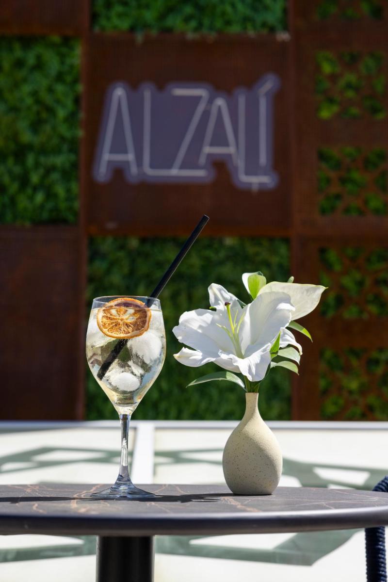 una copa de vino y una flor en una mesa en Cavalta Boutique Hotel - Small Luxury Hotels, en Sevilla