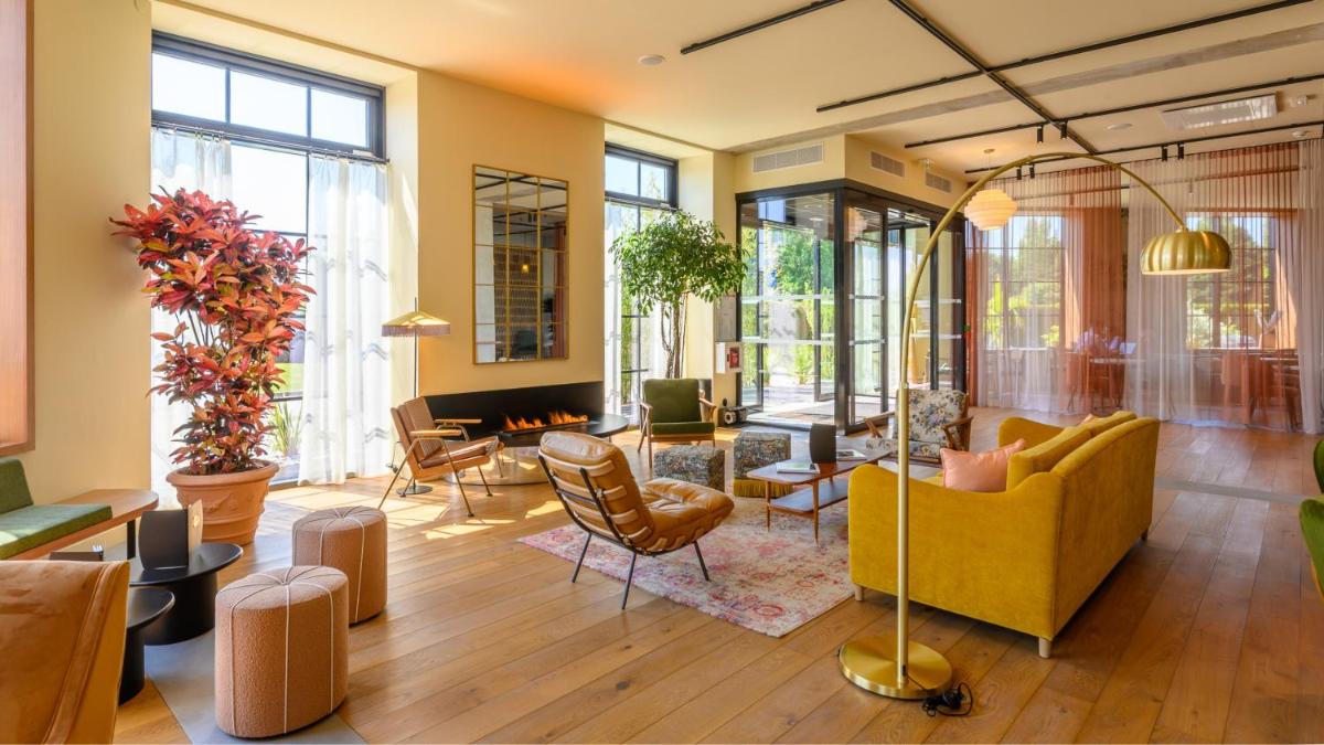 un salon avec un canapé et des chaises jaunes dans l'établissement Kyriad Prestige Compiègne Hotel & Spa, à Compiègne