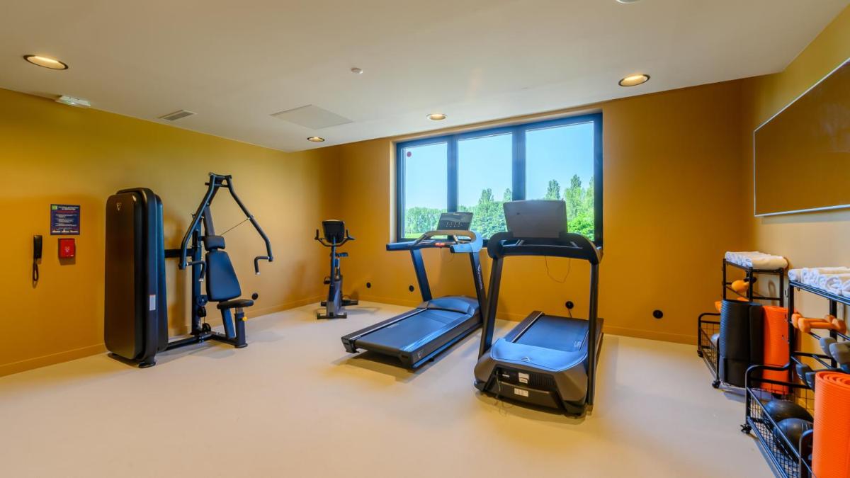 une salle de sport avec plusieurs tapis de course et un ordinateur portable dans l'établissement Kyriad Prestige Compiègne Hotel & Spa, à Compiègne 55 autres photos