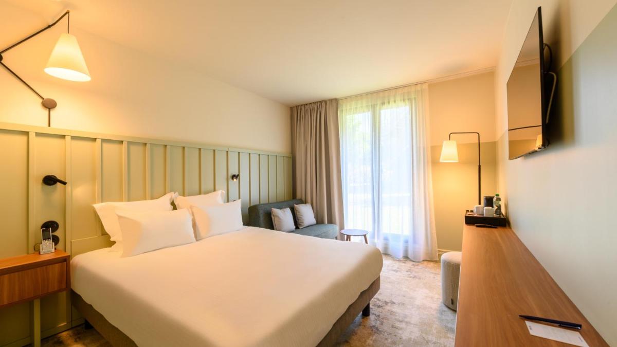 une chambre d'hôtel avec un lit blanc et une fenêtre dans l'établissement Kyriad Prestige Compiègne Hotel & Spa, à Compiègne
