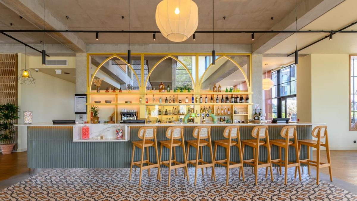 un bar avec une rangée de tabourets de bar dans l'établissement Kyriad Prestige Compiègne Hotel & Spa, à Compiègne