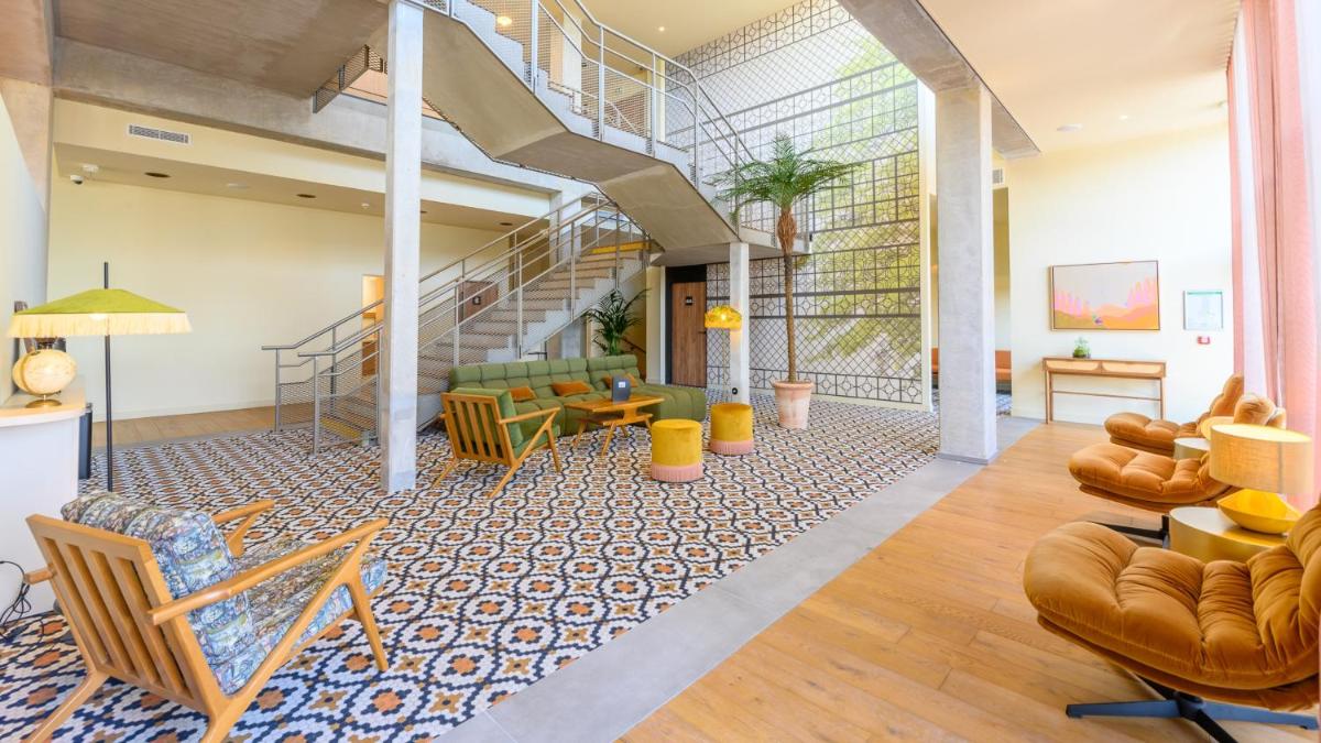 un salon avec un escalier, un canapé et des chaises dans l'établissement Kyriad Prestige Compiègne Hotel & Spa, à Compiègne
