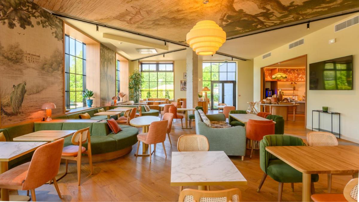 un restaurant avec des tables, des chaises et des fenêtres dans l'établissement Kyriad Prestige Compiègne Hotel & Spa, à Compiègne