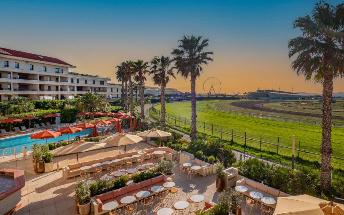 un hôtel avec piscine et palmiers et un complexe hôtelier dans l'établissement Hôtel Villa M Marseille, à Marseille un hôtel avec piscine et palmiers et un complexe hôtelier dans l'établissement Hôtel Villa M Marseille, à Marseille