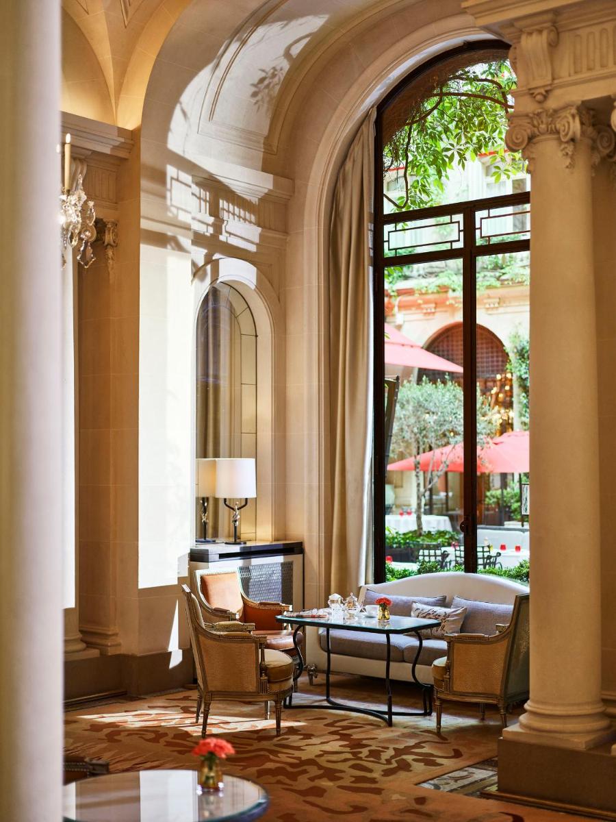 un hall avec une table et des chaises dans un bâtiment dans l'établissement Hôtel Plaza Athénée - Dorchester Collection, à Paris