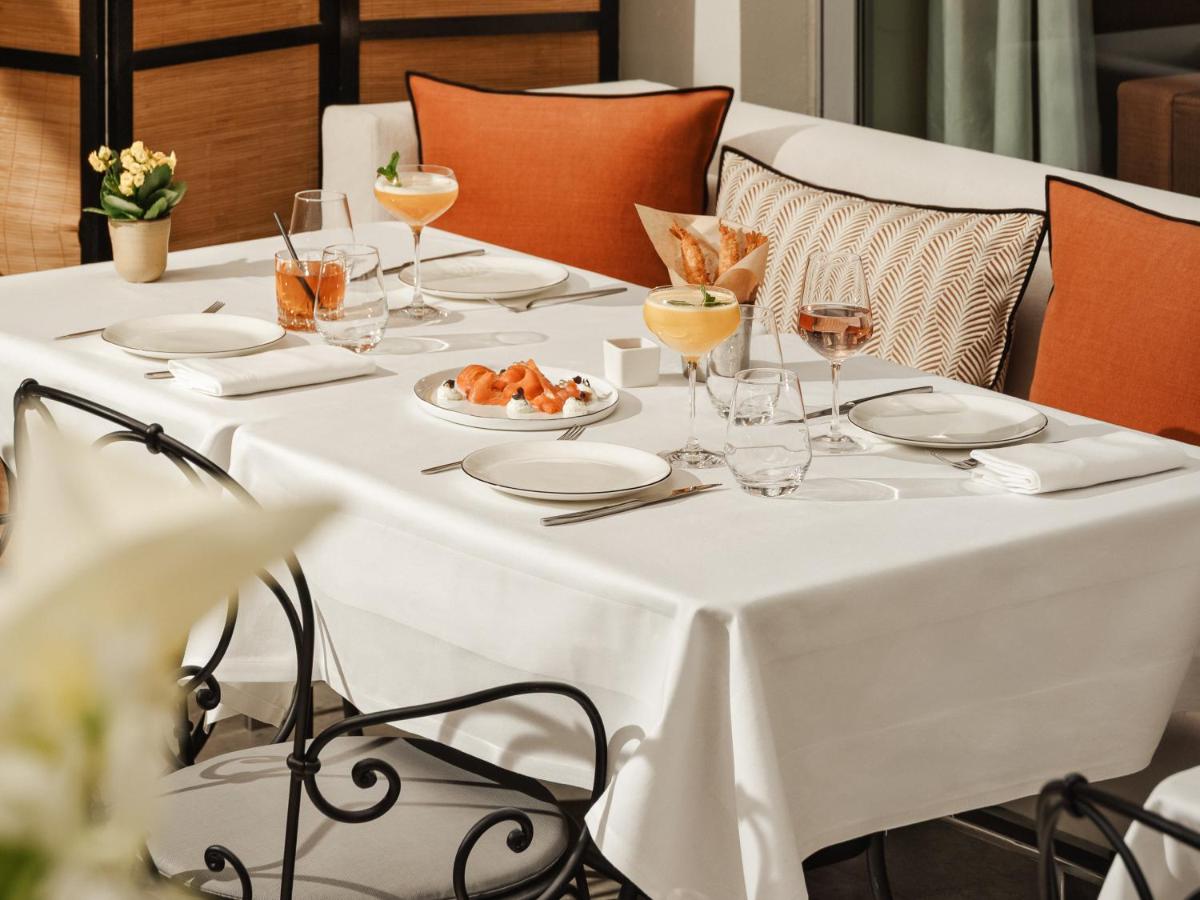 une table blanche avec des verres et une assiette de nourriture dans l'établissement Hôtel De Sers Champs Elysées Paris, à Paris