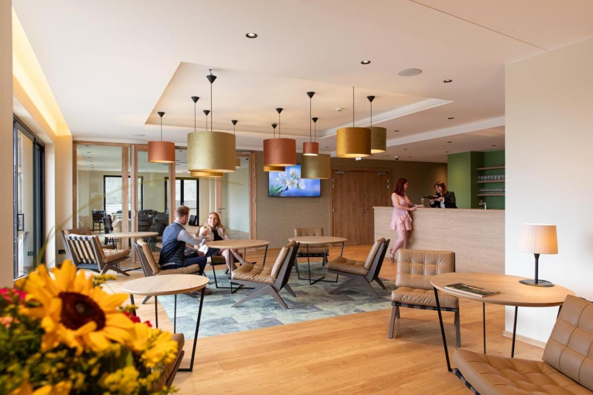 un hall d'hôtel avec des gens assis à des tables dans l'établissement Hôtel Terra Vinum, à Gueberschwihr
