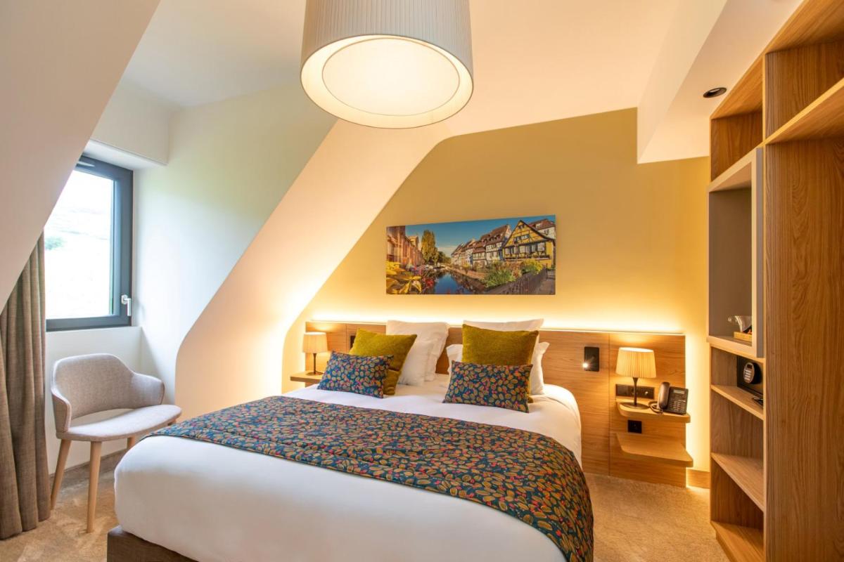une chambre d'hôtel avec un lit et une chaise dans l'établissement Hôtel Terra Vinum, à Gueberschwihr