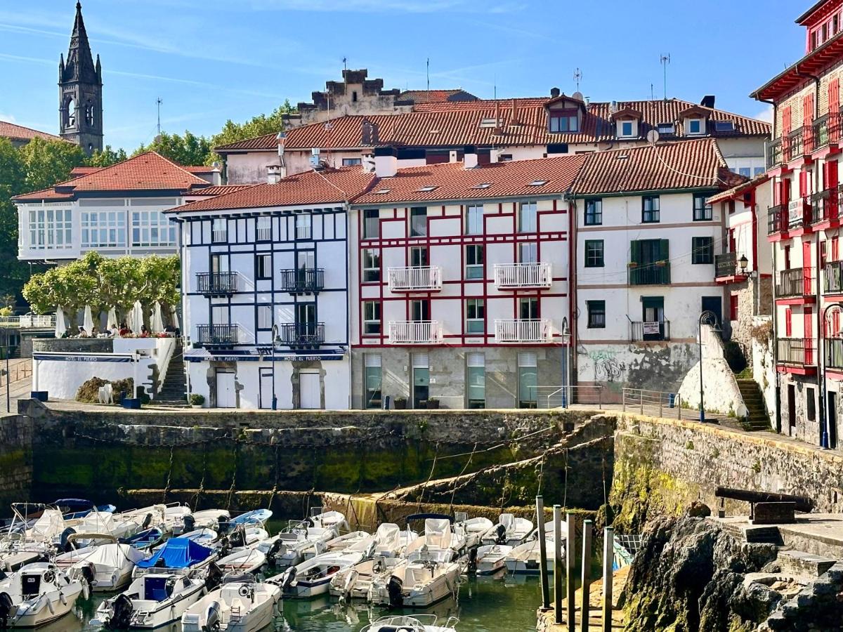 Un grupo de barcos atracados en un puerto con edificios. en Apartamentos&Spa Mundakaport, en Mundaka