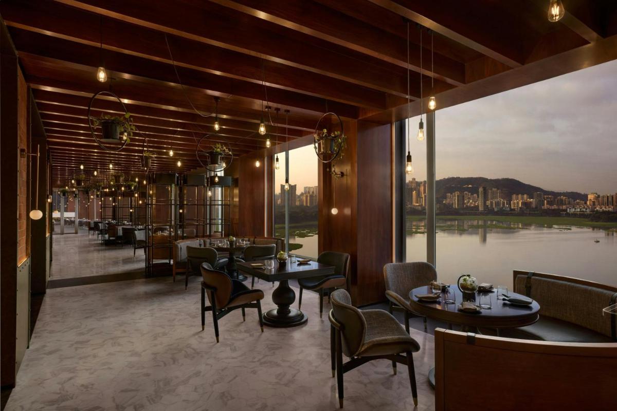 a restaurant with tables and chairs and a large window at The Westin Mumbai Powai Lake in Mumbai