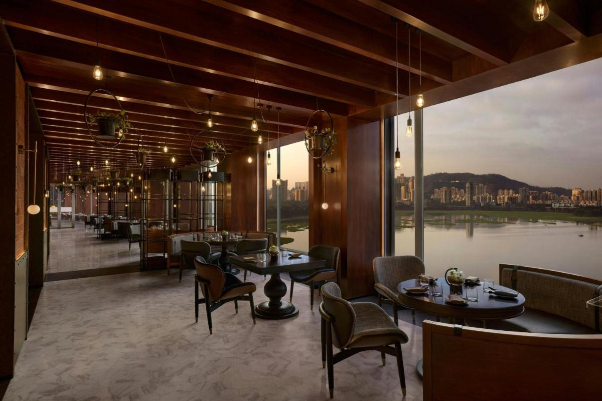 a restaurant with tables and chairs and a large window at The Westin Mumbai Powai Lake in Mumbai