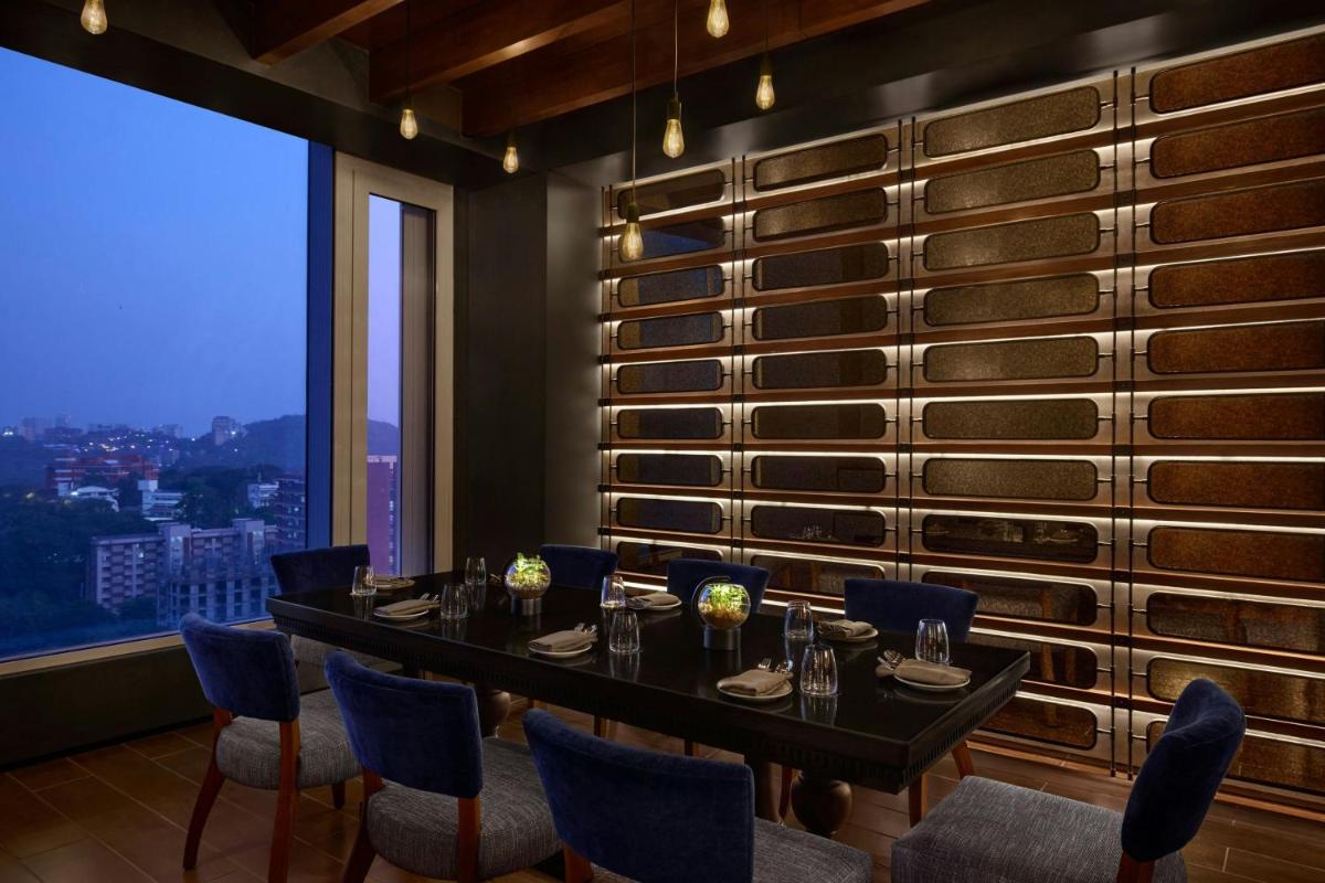 a dining room with a table and chairs and a window at The Westin Mumbai Powai Lake in Mumbai
