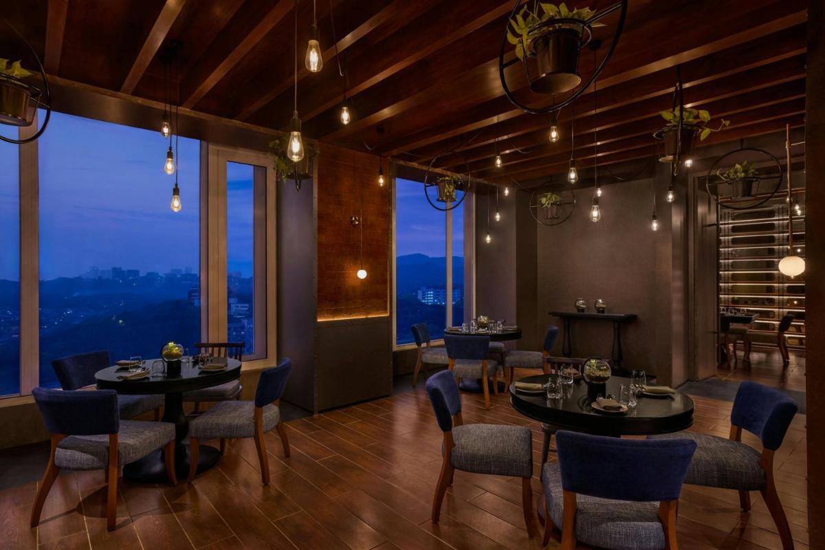 a restaurant with tables and chairs and large windows at The Westin Mumbai Powai Lake in Mumbai
