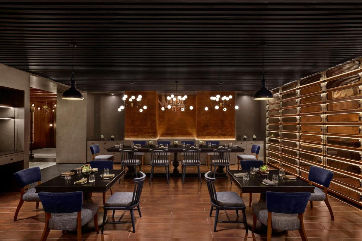 a large dining room with tables and chairs and wine racks at The Westin Mumbai Powai Lake in Mumbai