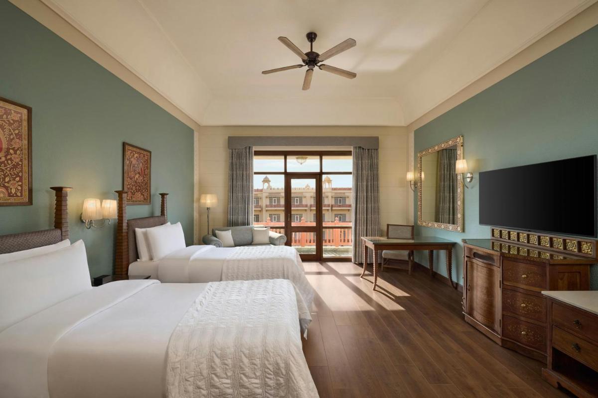a hotel room with two beds and a flat screen tv at Le Meridien Jaipur Resort & Spa in Jaipur