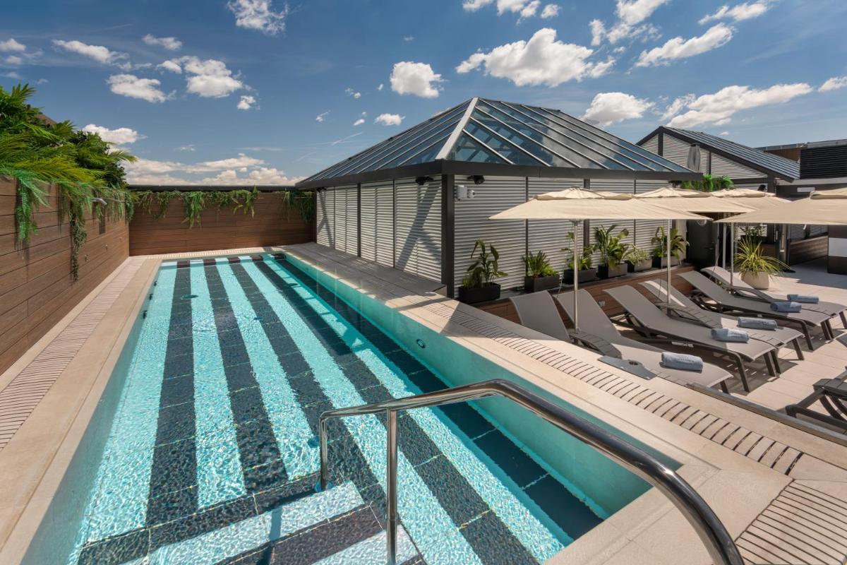 una piscina al aire libre con sillas y sombrillas en Catalonia Plaza España Hotel & Spa, en Madrid