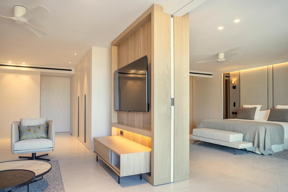 Un dormitorio con una cama, un televisor y una silla. en Insotel Fenicia Prestige Suites & Spa, en Santa Eulària des Riu