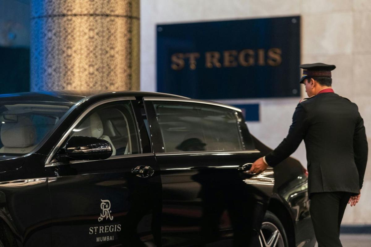 a man in a military uniform standing next to a car at The St. Regis Mumbai in Mumbai