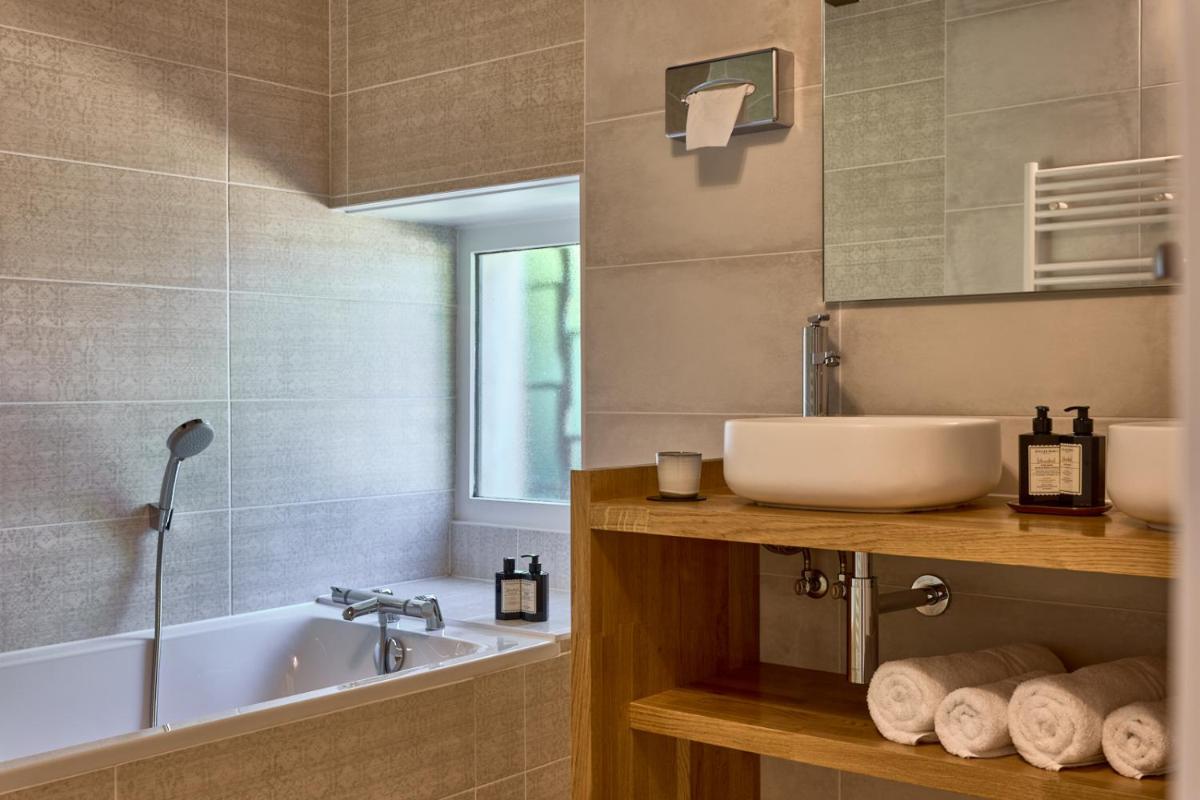 une salle de bain avec un lavabo et une baignoire dans l'établissement Maison Zugno Hôtel & Spa, à Barretaine