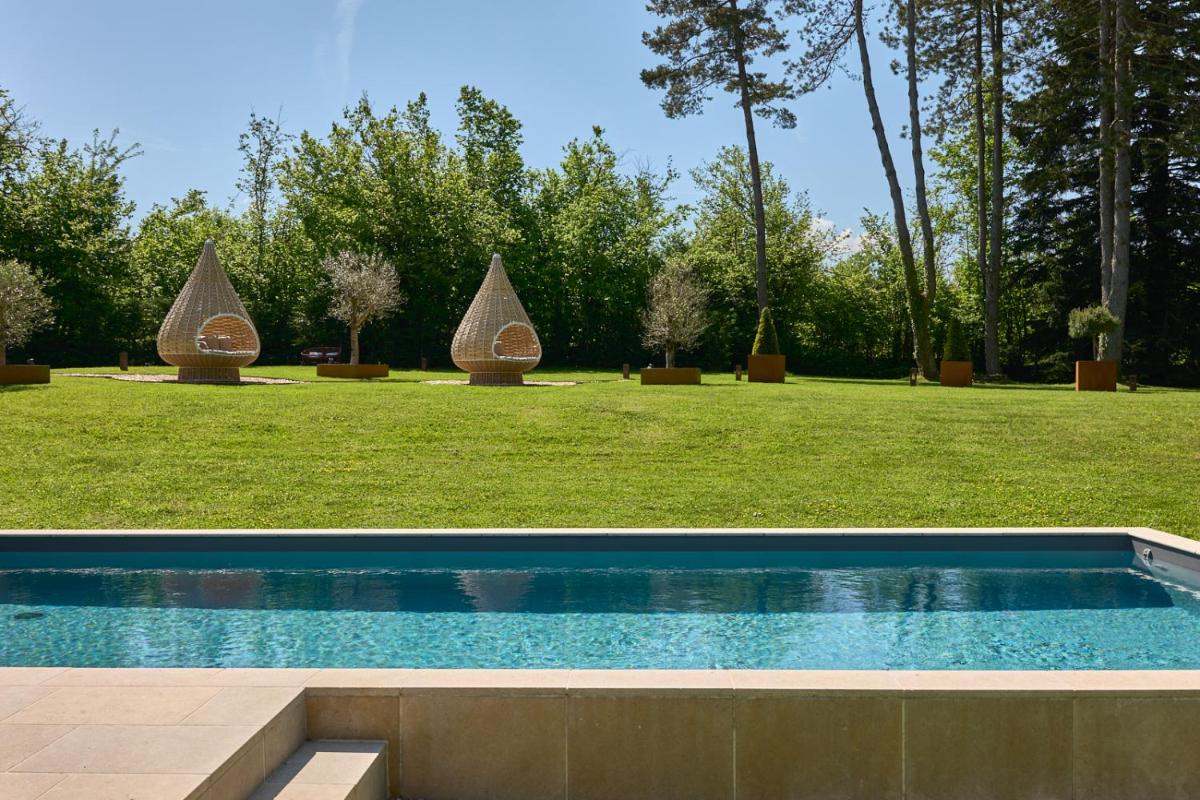 une piscine au milieu d'un champ avec des arbres dans l'établissement Maison Zugno Hôtel & Spa, à Barretaine