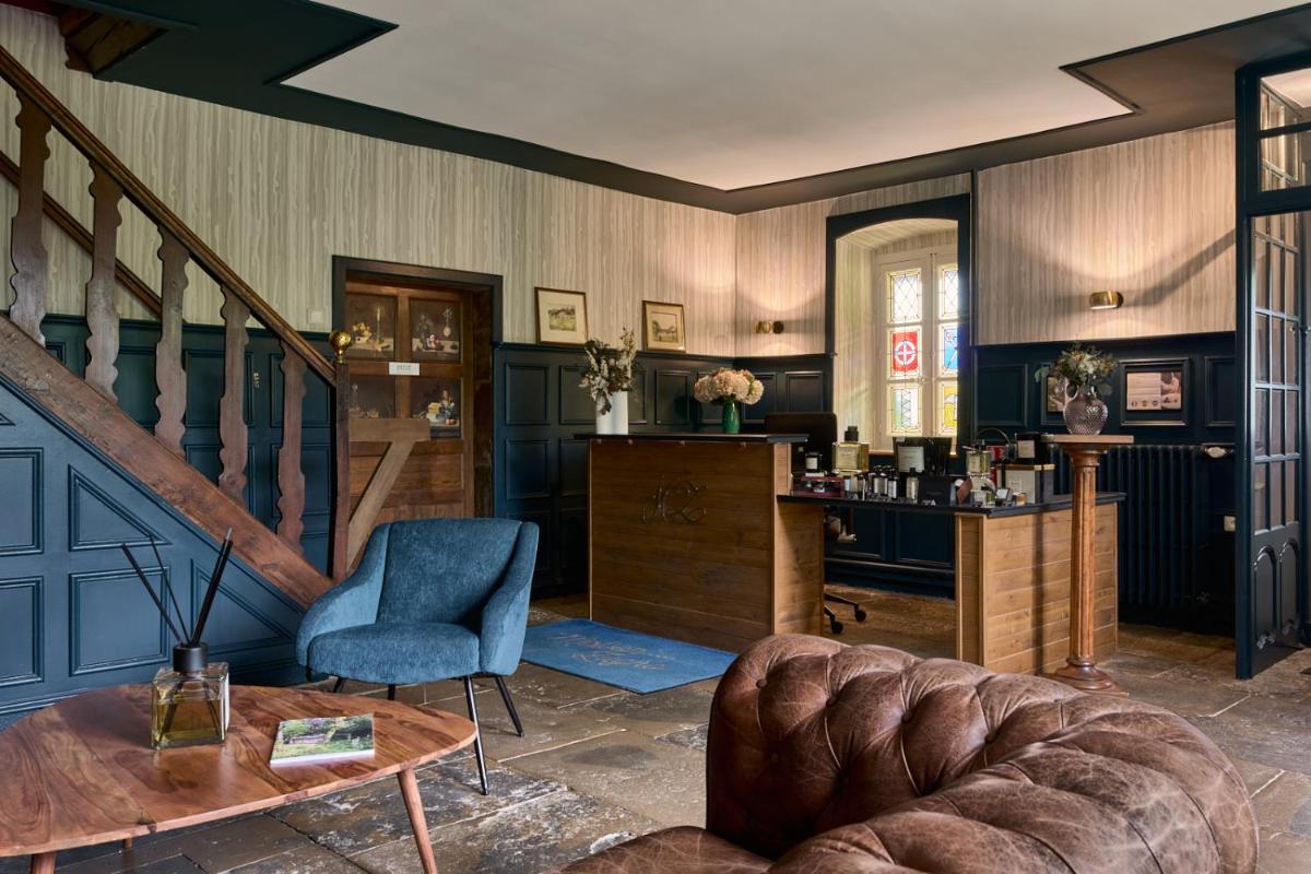 un salon avec un escalier et une chaise bleue dans l'établissement Maison Zugno Hôtel & Spa, à Barretaine