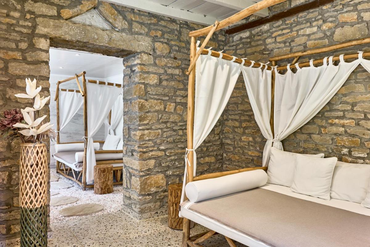 une chambre aux murs de pierre avec un lit et un miroir dans l'établissement Maison Zugno Hôtel & Spa, à Barretaine