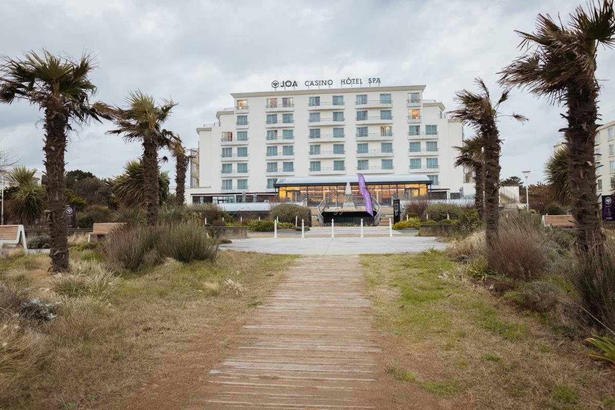 un grand bâtiment avec des palmiers devant dans l'établissement Hôtel Spa du Beryl St Brévin l'Océan, à Saint-Brévin-les-Pins