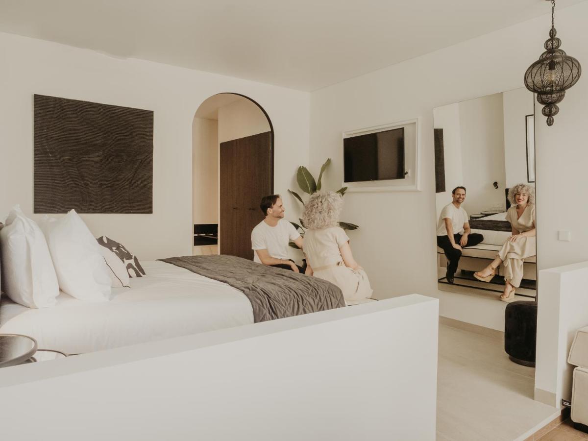 Un grupo de personas sentadas en una cama en un dormitorio. en Comfy Studios Hotel, en Benalmádena