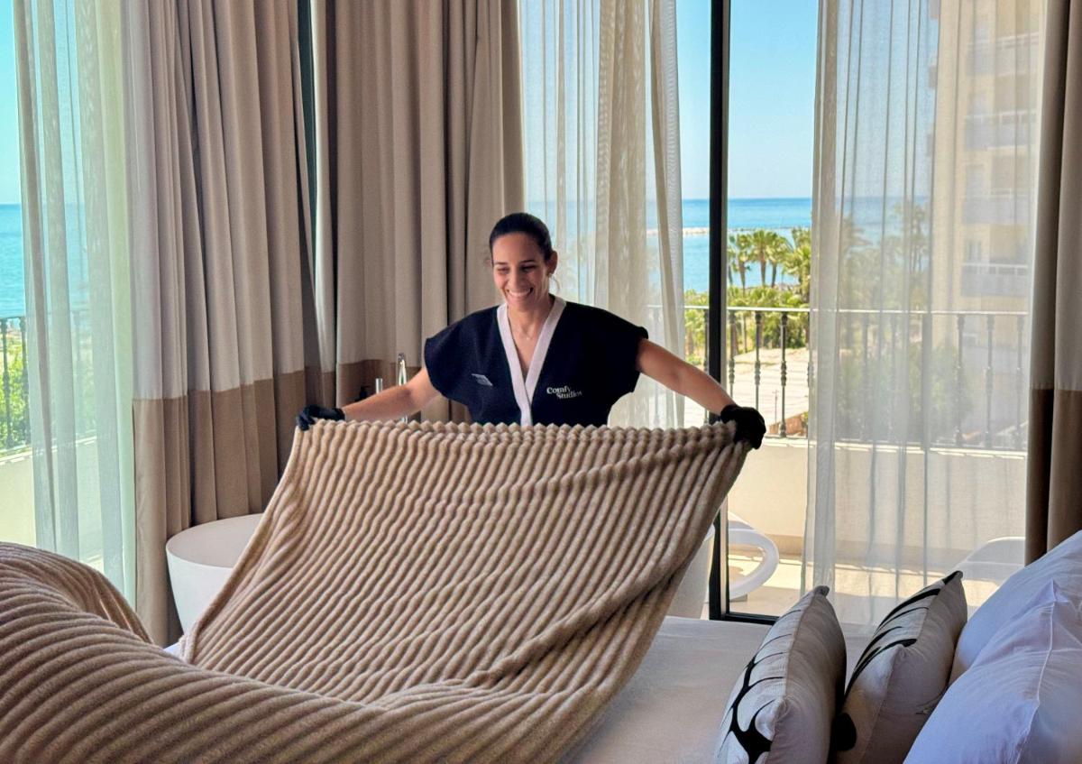 una mujer parada en una habitación de hotel con una cama en Comfy Studios Hotel, en Benalmádena