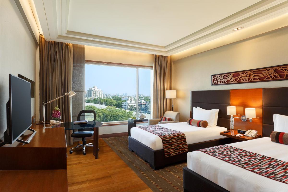 a hotel room with two beds and a desk and a window at Crowne Plaza Today Gurugram by IHG in Gurgaon a hotel room with two beds and a desk and a window at Crowne Plaza Today Gurugram by IHG in Gurgaon
