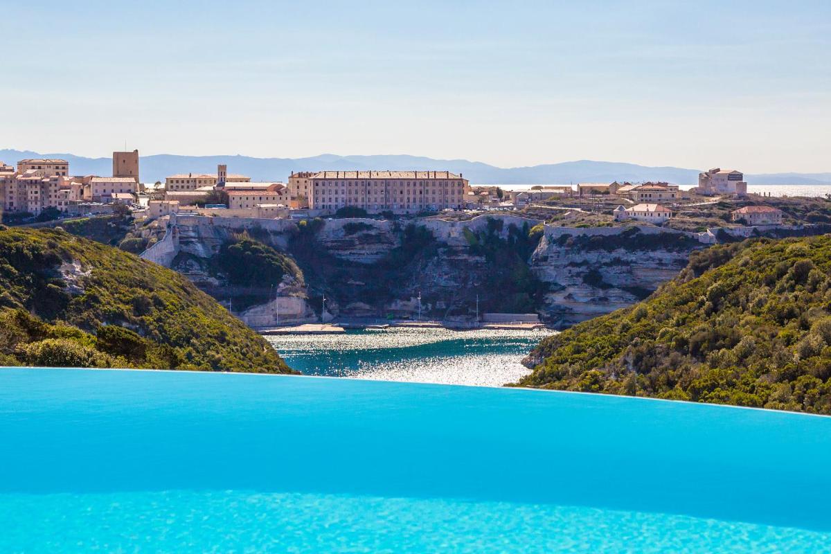 une vue sur une rivière avec une ville en arrière-plan dans l'établissement Hôtel Cala di Greco, à Bonifacio