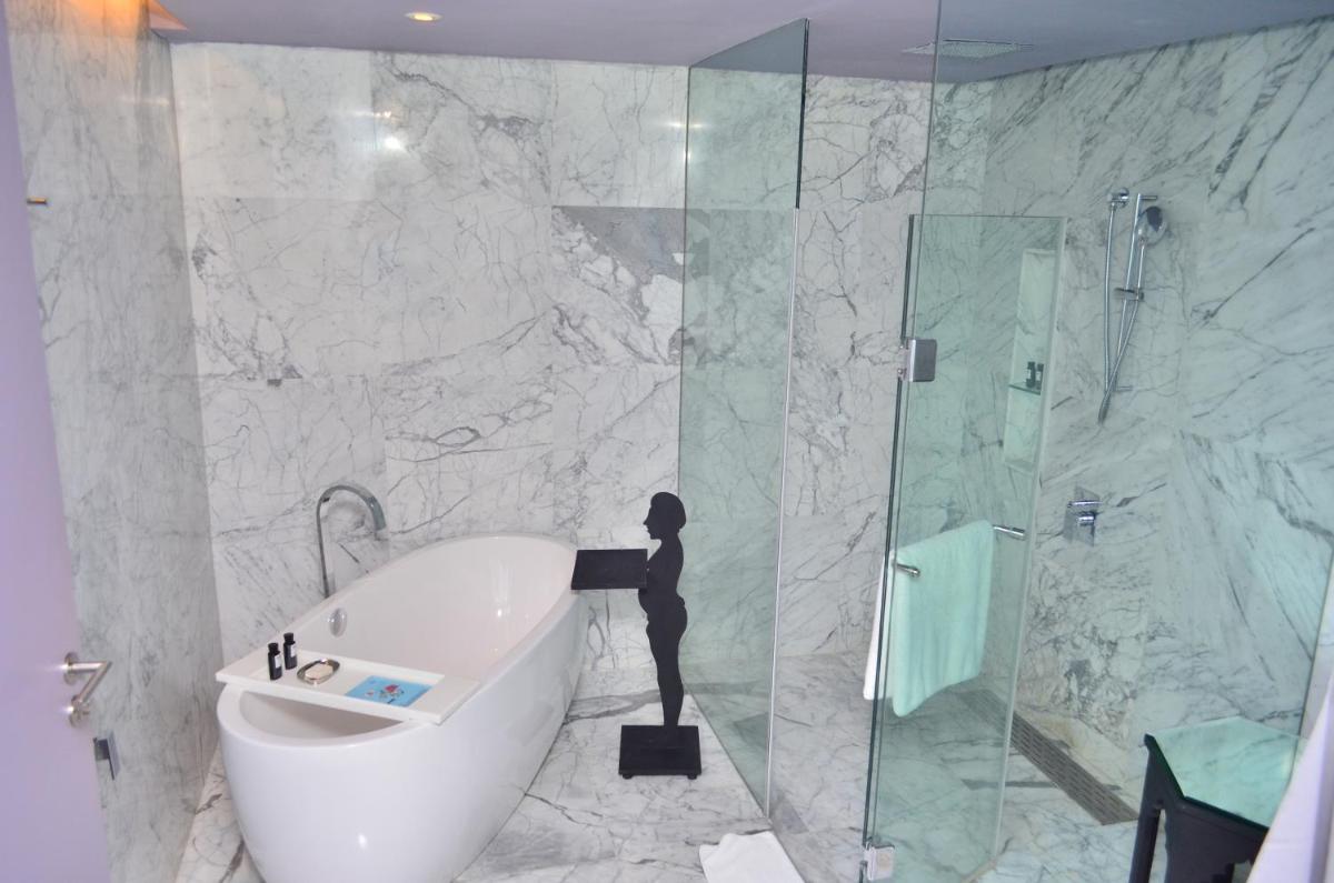 a bathroom with a tub and a glass shower at The Park Hyderabad, Banjara Hills near Hussain Sagar Lake in Hyderabad a bathroom with a tub and a glass shower at The Park Hyderabad, Banjara Hills near Hussain Sagar Lake in Hyderabad