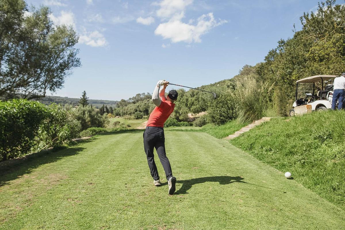 un hombre balanceando un palo de golf en un campo en Reserva Rotana Golf Resort, en Manacor