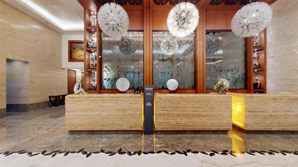 a lobby with a reception desk and chandeliers at Radisson Blu Hotel, Nagpur in Nagpur