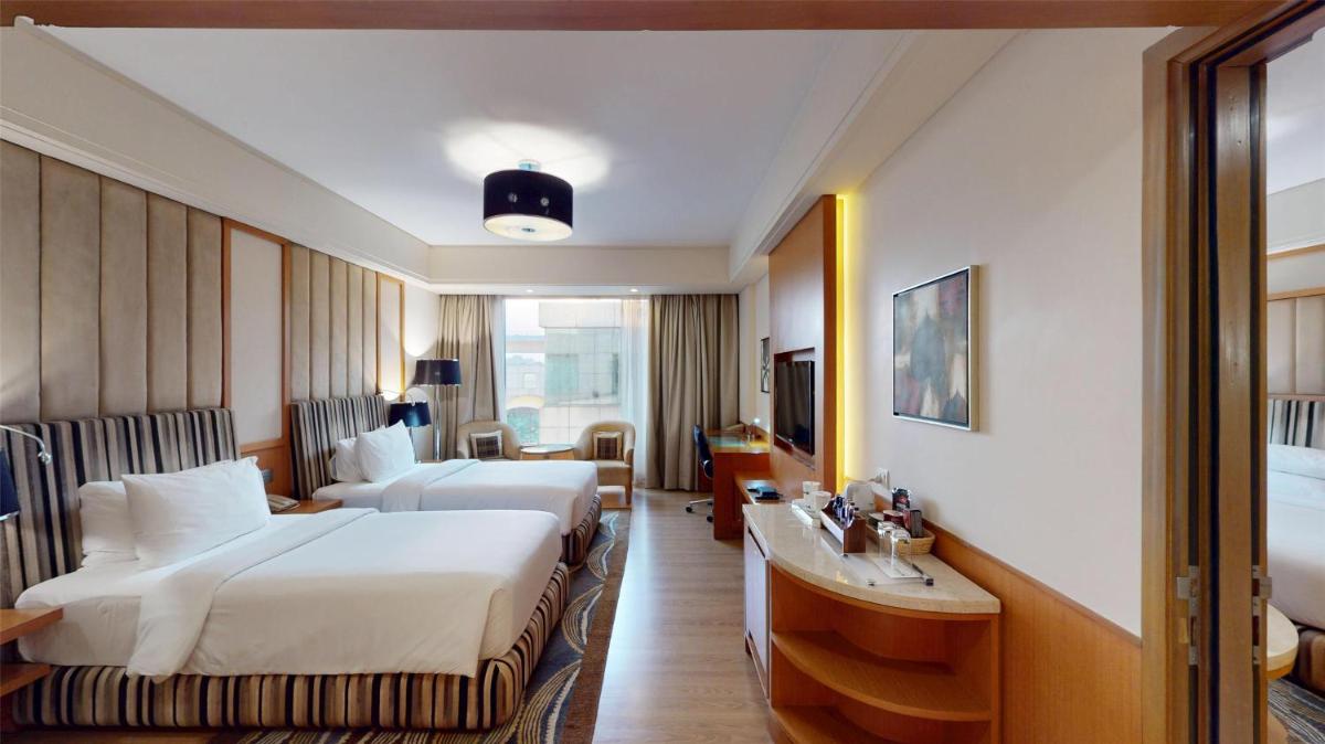 a hotel room with two beds and a desk at Radisson Blu Hotel, Nagpur in Nagpur