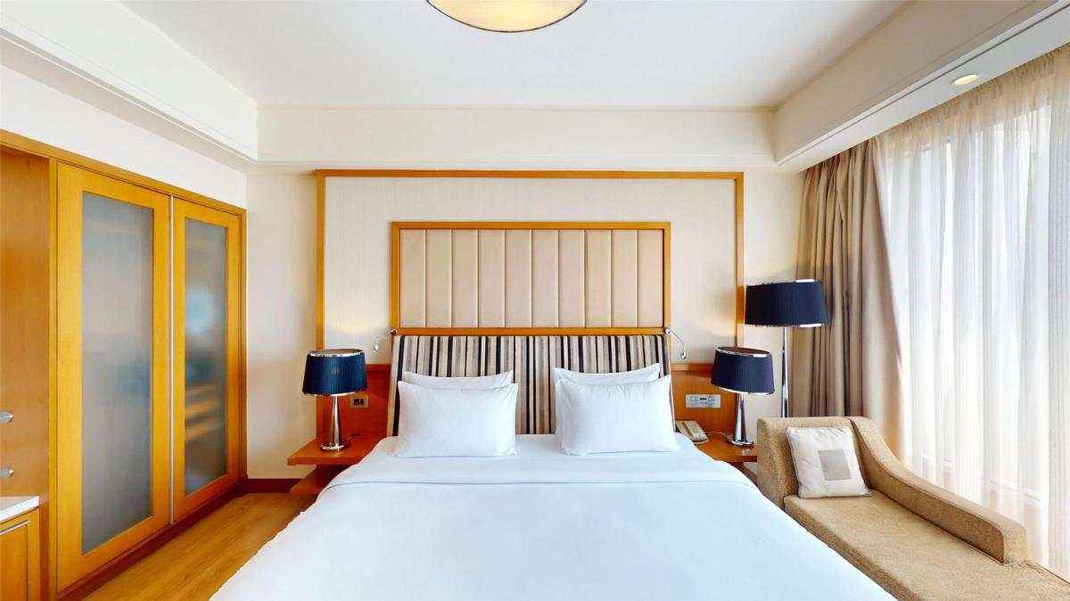 a bedroom with a large white bed and two lamps at Radisson Blu Hotel, Nagpur in Nagpur