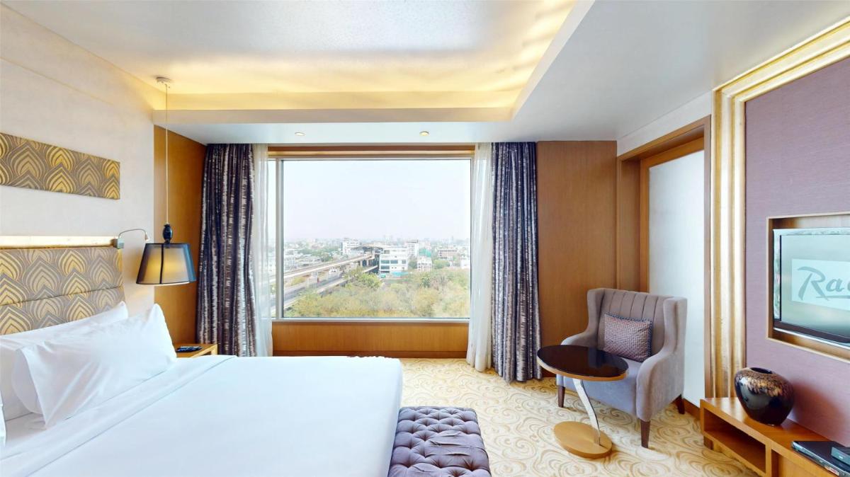a hotel room with a bed and a large window at Radisson Blu Hotel, Nagpur in Nagpur