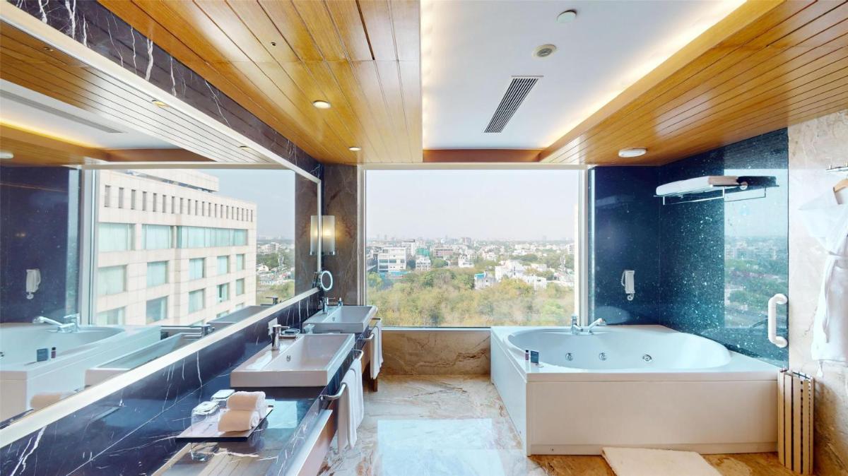 a bathroom with two sinks and a tub and a large window at Radisson Blu Hotel, Nagpur in Nagpur