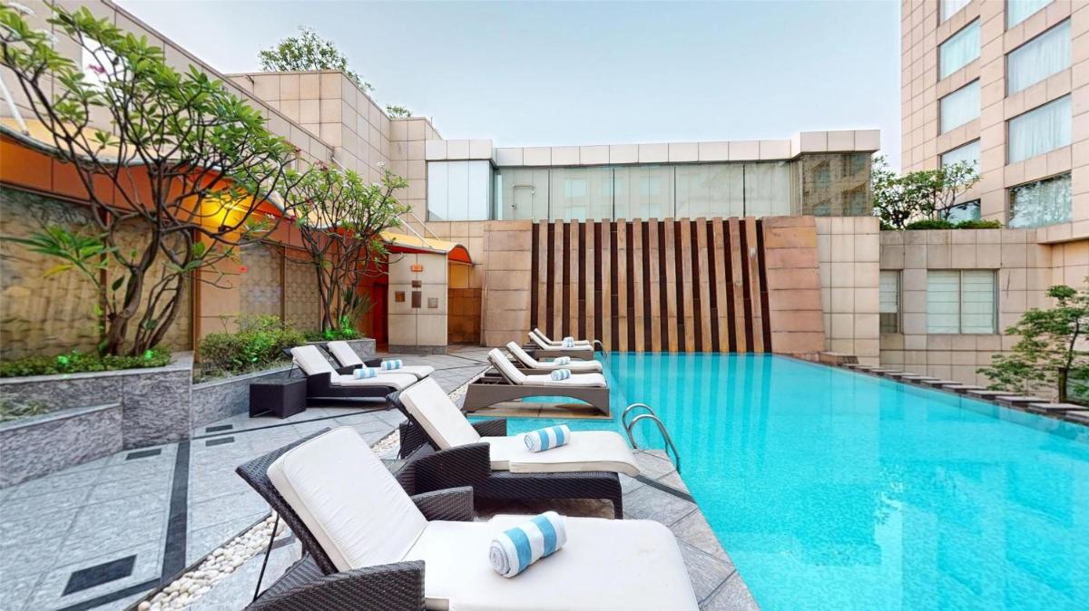 a swimming pool with lounge chairs next to a building at Radisson Blu Hotel, Nagpur in Nagpur