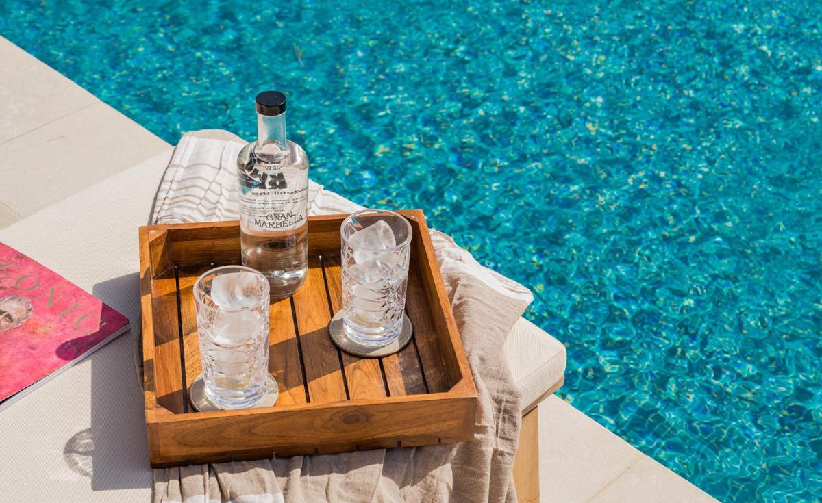 Una botella y vasos en una caja junto a una piscina en Gran Marbella Resort & Beach Club, en Marbella