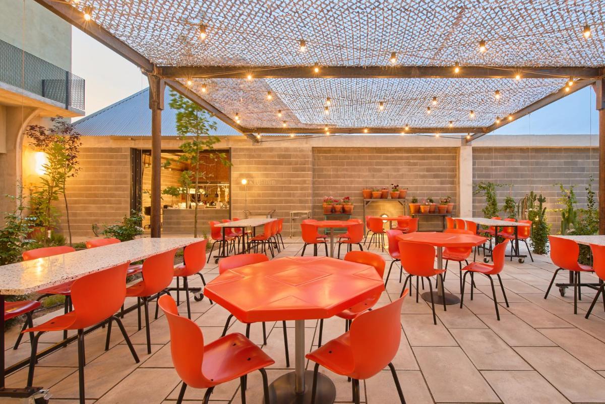 um pátio exterior com mesas, cadeiras e luzes em Moagem Industrial Lodge em Viana do Alentejo