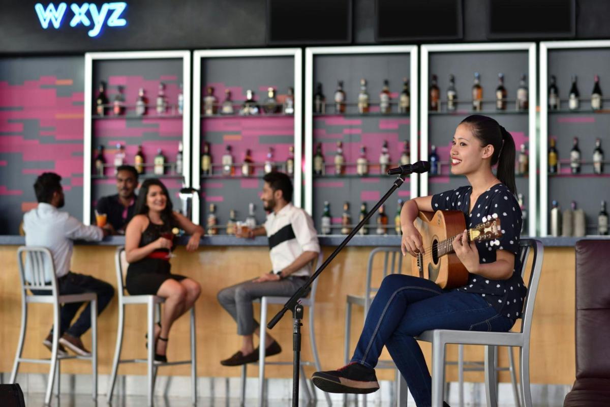 a woman sitting in a chair with a microphone at Aloft Bengaluru Outer Ring Road in Bengaluru