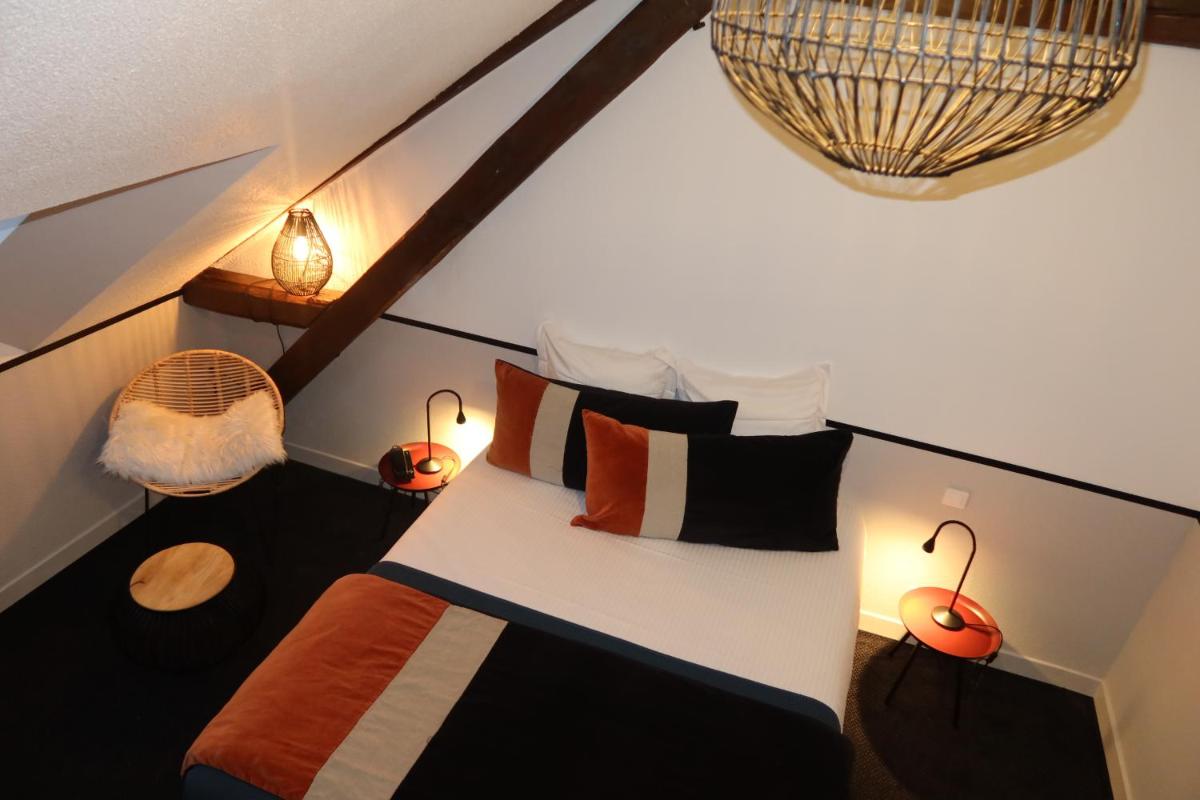 une chambre avec un lit avec des oreillers et des lampes dans l'établissement Hotel Spa Azteca Barcelonnette, à Barcelonnette