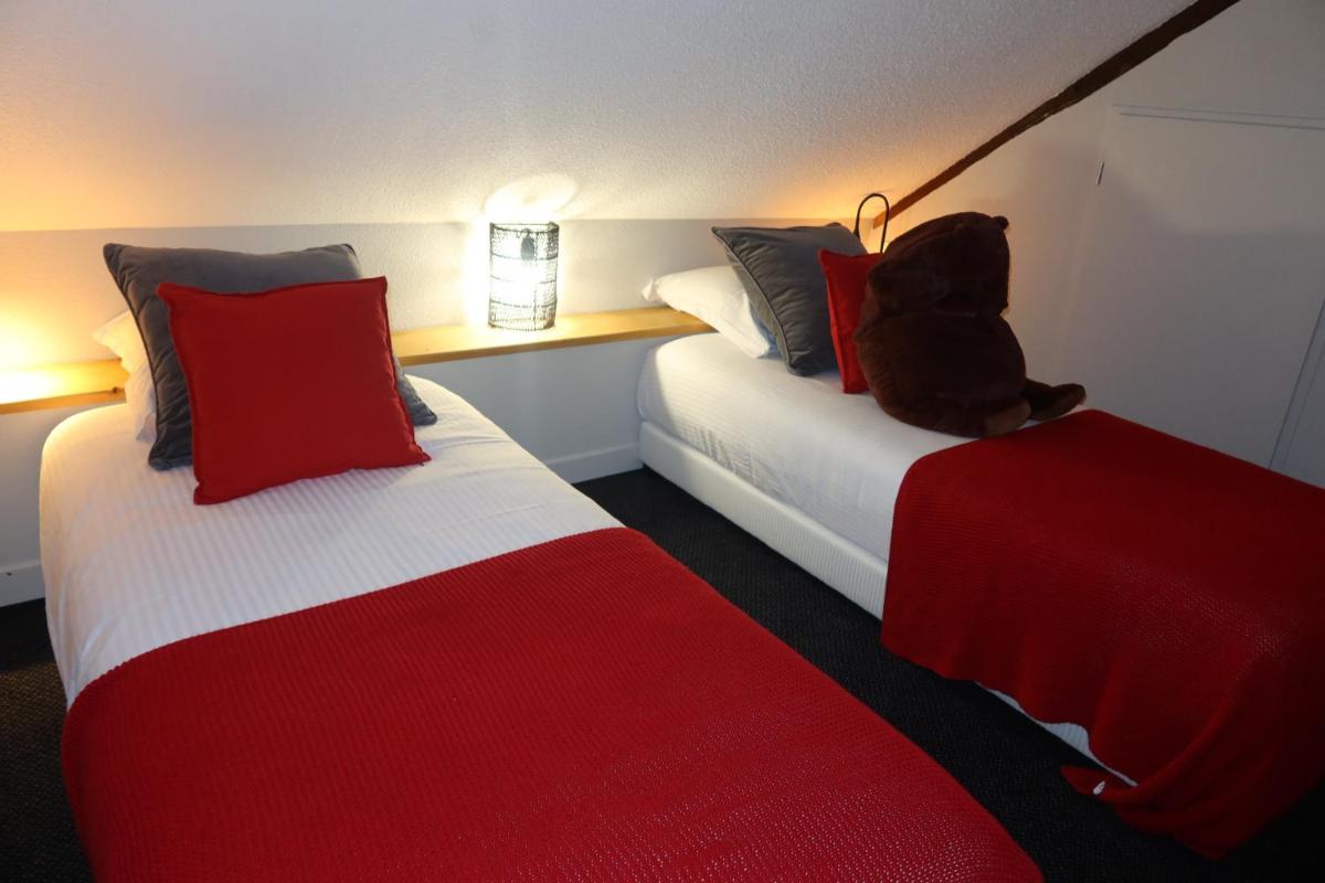 Cette chambre d'hôtel comprend 2 lits avec un ours en peluche assis au-dessus. dans l'établissement Hotel Spa Azteca Barcelonnette, à Barcelonnette