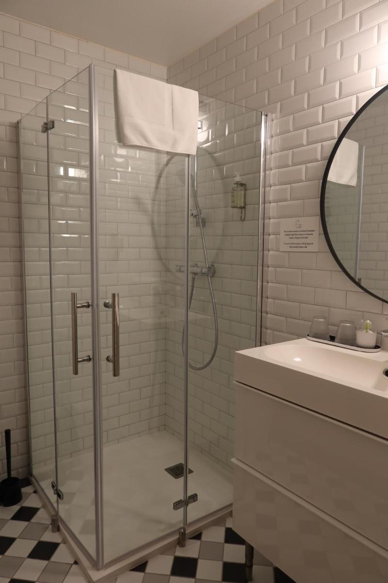 une douche en verre dans une salle de bain avec un lavabo dans l'établissement Hotel Spa Azteca Barcelonnette, à Barcelonnette