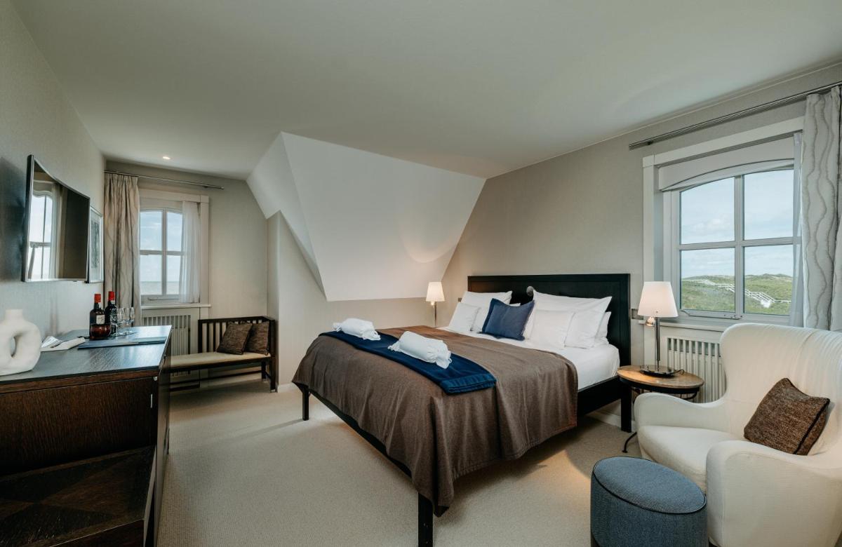 ein Hotelzimmer mit einem Bett und einem Stuhl in der Unterkunft Söl'ring Hof in Rantum